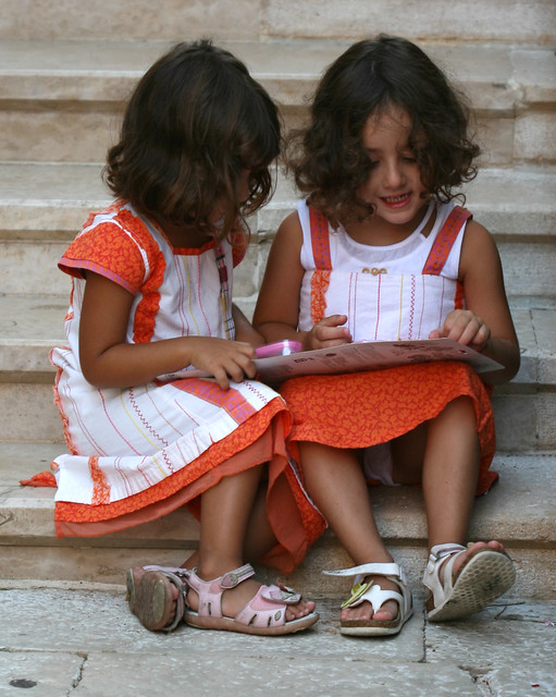 Two little girls playing on the steps in a church courtyard Pore Croatia