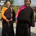 Ladakhi daughter & mother smiling in brown wool chubas, bright shirts, Dharma bag, advanced practicioner's mala, and red ritual blindfold. In Boudhi, Western Archaic Tibetan, mom said you should take our picture, Tibetan Buddhism, Boudha, Nepal