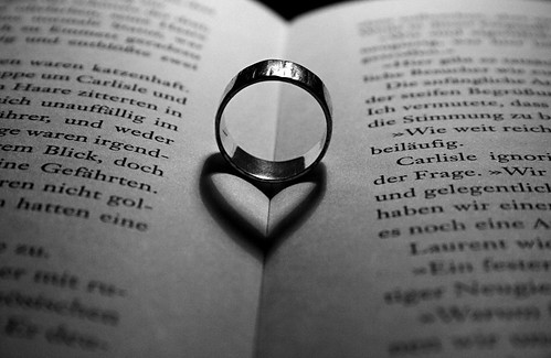 Photograph of ring in open spine of book, casting shadow of a heart