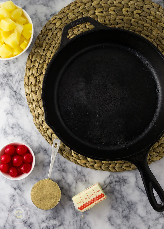 cast iron skillet with pineapple cake ingredients surrounding on marble