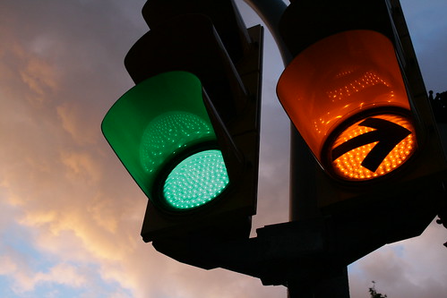 Traffic lights: one green lamp and one orange right-turn arrow.