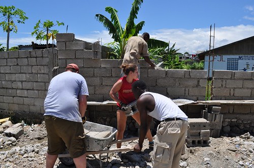 Volunteers mixing cement and placing bricks for security wall