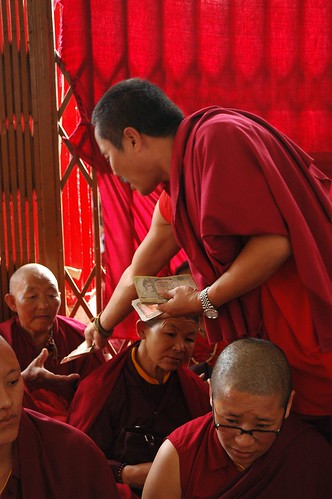 Donate to nuns first! A Tibetan Monk passing out monetary donations to an elder Sakya nun sitting on the front porch, monks & lay people under tent, Tharlam Monastery of Tibetan Buddhism, Sakya Lamdre, Boudha, Kathmandu, Nepal by Wonderlane