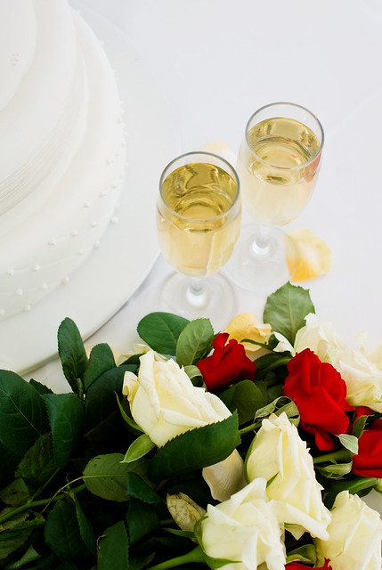 Bridal Bouquet of Roses With Wedding Reception Cake and Glasses of Champagne
