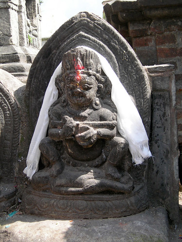 Protector of the Dharma, Shri Mahakala standing on a corpse, wearing tika, white ritual khatak, holding vajra stick, ritual objects, concrete statue, Swayambhunath Stupa, Manjushri Hill, Kathmandu, Nepal by Wonderlane