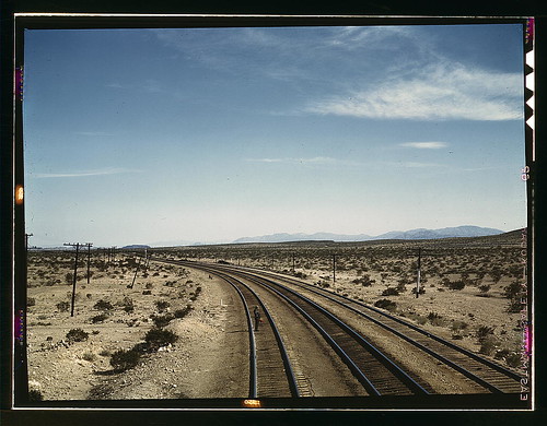 Flagman standing at a distance behind a Santa Fe R.R. west bound freight train during a stop, Bagdad, Calif. (LOC) by The Library of Congress