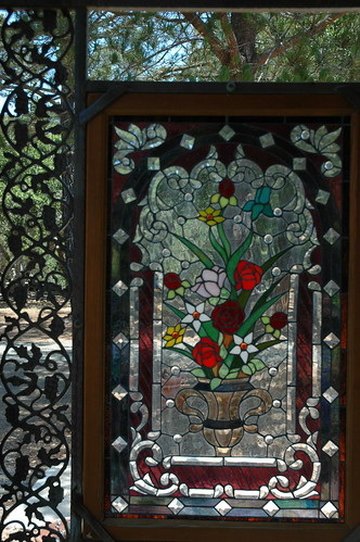 Stained glass window, metal iron work, trophy vase of flowers, tree, Cambria Cemetery, California, USA by Wonderlane