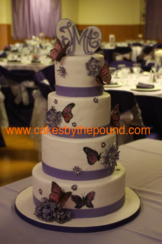 The wedding cake has painted butterflies sugar flowers and sugar butterflys