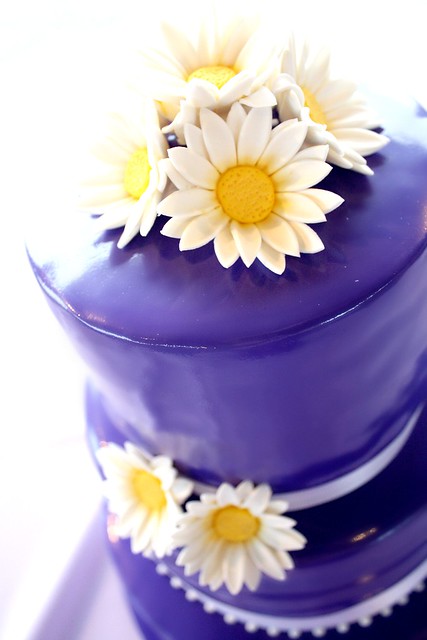 Purple wedding cake with handmade sugar daisies The cake has a little shine 