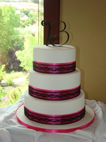 3 tier wedding cake wrapped with a hot pink satin ribbon and black lace