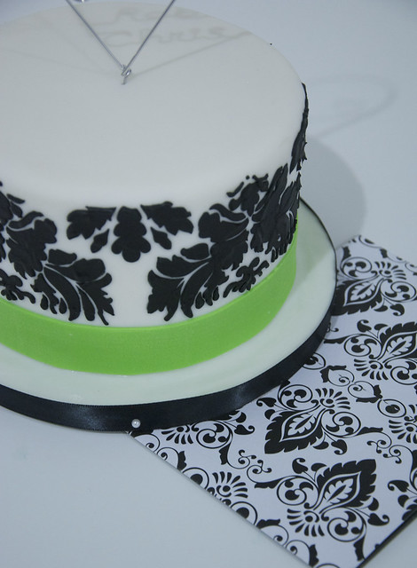 A small white fondant wedding cake with a black damask print and an apple 