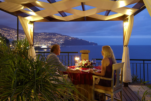 coppia che cena su una veranda molto elegante di fronte ad una baia