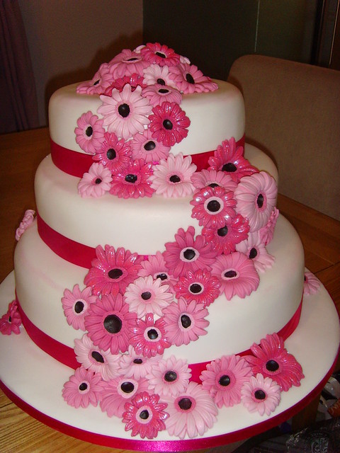 Sparkly pink gerbera stacked wedding cake with dark pink ribbon and edging