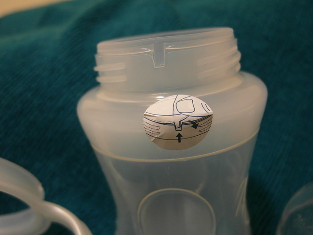Nuby 矽膠奶瓶3階段訓練杯：有教學貼紙，只要將尖凸卡榫往內推就可以把環蓋與杯身分離
