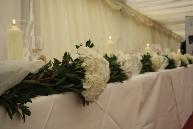 Top table garland using hydrangeas and hurricane vases for marquee wedding