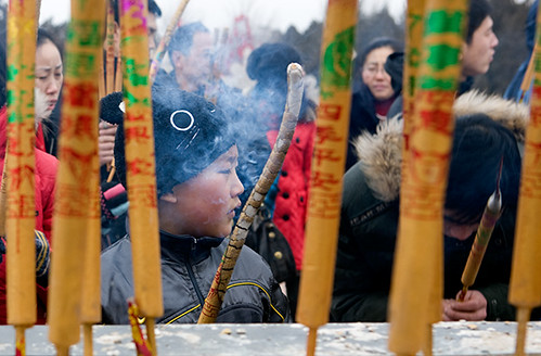 Boy prays with incense during a temple fair at  the Temple of Earth in Beijing on the first day of the Chinese Lunar New Year of Tiger.