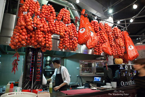 Various tomatoes and jamon hanging over a section of the bar