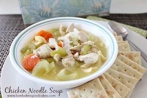 Chicken Noodle Soup in bowl with crackers and spoon.