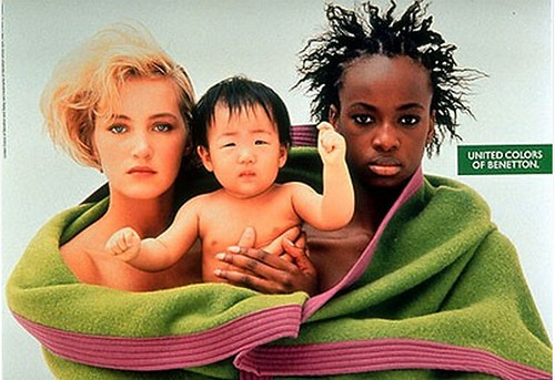 A Benetton ad featuring a white woman, a black woman, and an Asian baby all wrapped in a big blanket 