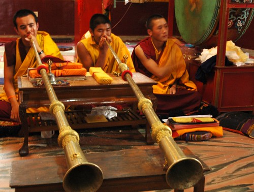 Tibetan monks playing long horns propped up on a table, beating the big green leather drum, prayer books on a pillow, Sakya Lamdre, Tharlam Monastery of Tibetan Buddhism, Boudha, Kathmandu, Nepal by Wonderlane