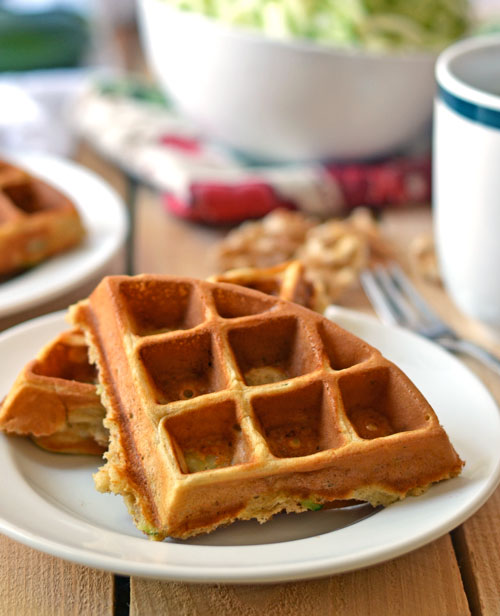 Two triangles of whole wheat zucchini waffles on a white plate