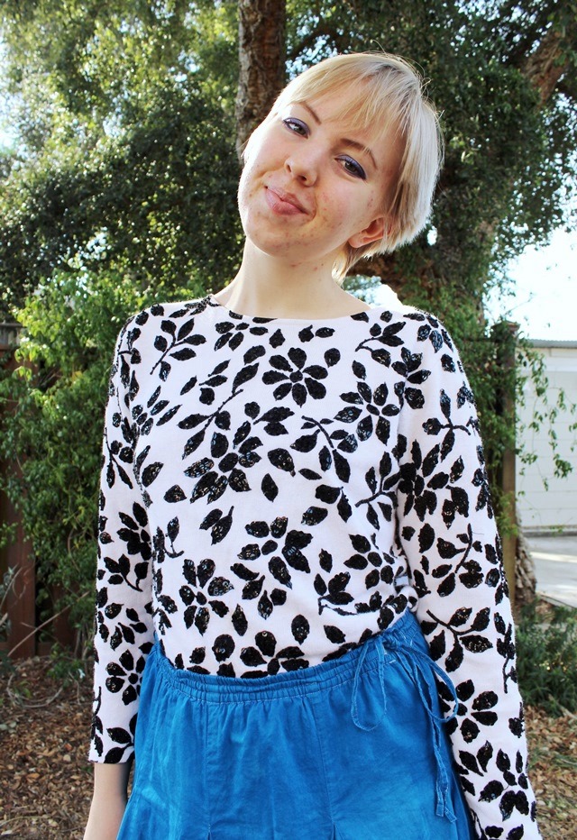 black-and-white floral blouse tucked into bright blue skirt