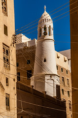Power lines, mosque minaret and buildings made of adobe mud - desert city of Shibbam