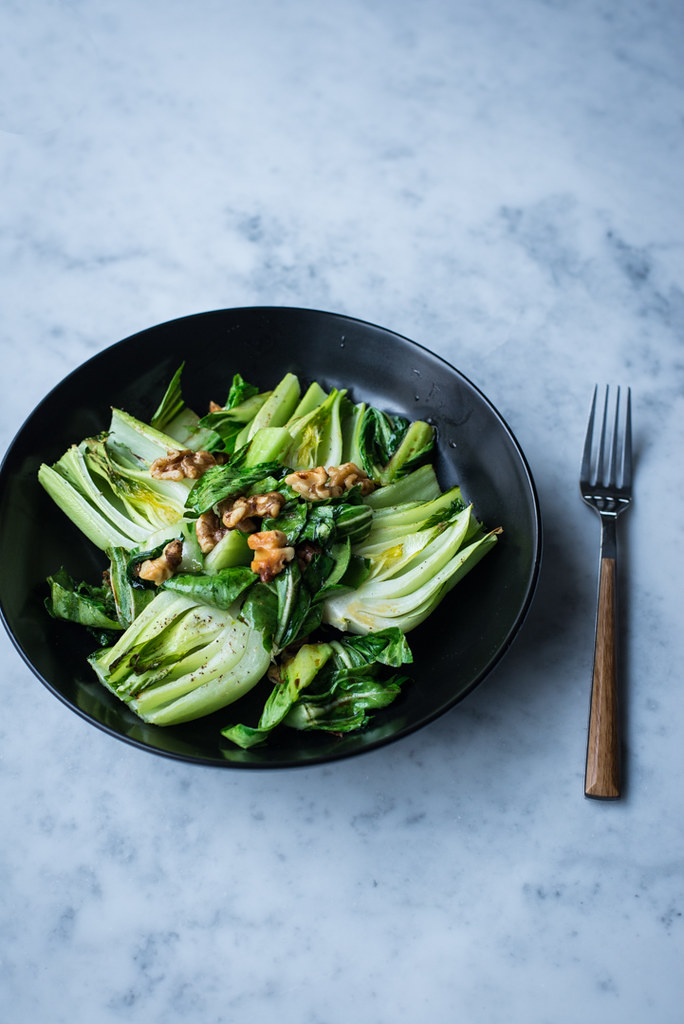 Simple Roasted Baby Bok Choy with walnuts in black bowl