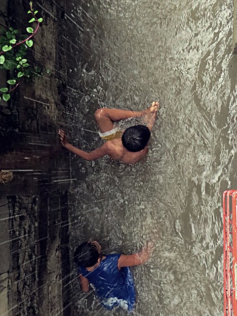 A young boy checking his foot, as he felt he stepped on something while playing in the flood.  Photographed by Bernard Eirrol Tugade