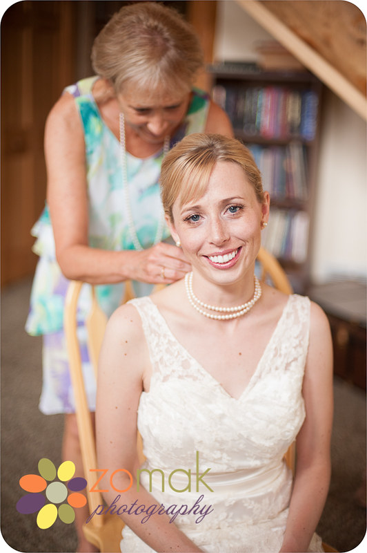 The bride's mother gently clasps a family heirloom necklace.
