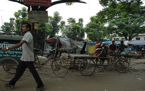 Man out for a stride, rickshaw drivers, carts, men taking a break, plastic tent, rickshaw capital of the world, dirt road, trees, Dhania, Dhaka, Bangladesh by Wonderlane