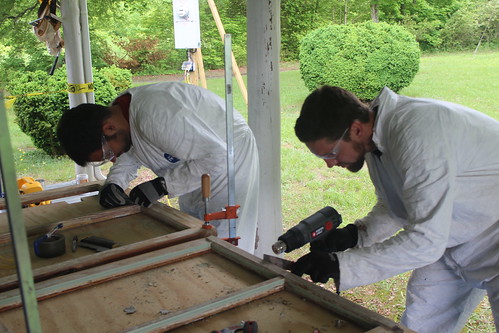 Military veteran Tyler Price, left, of the Student Conservation Association, and Josh Carr of Historicorps scrape lead paint off of historic window sashes of a Thornburg Farm historic building during a restoration project on the Uwharrie National Forest. (Photo courtesy Michael Salisbury)