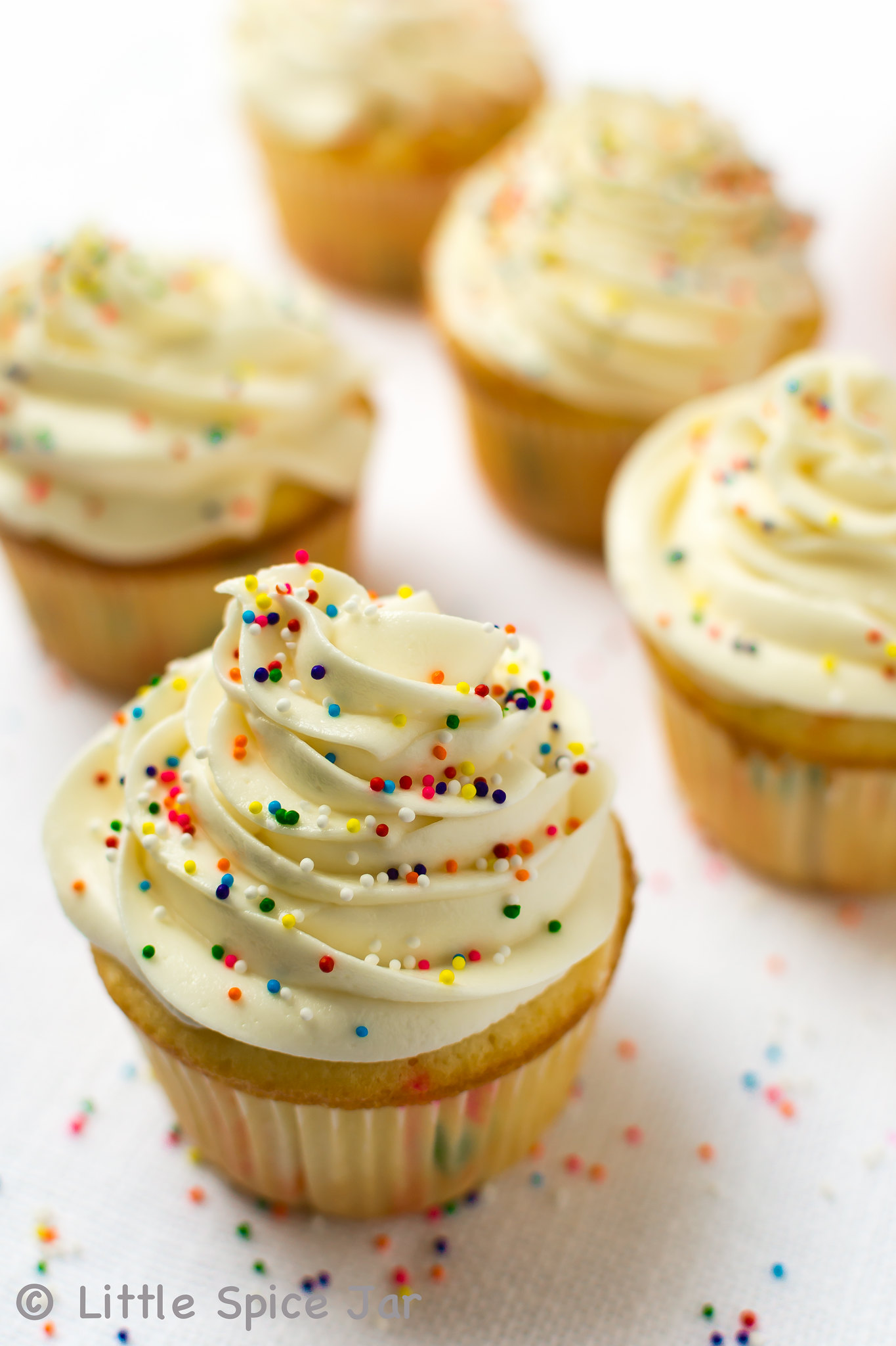 close up of vanilla cupcake with buttercream and sprinkles on top