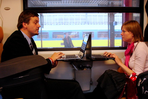 Man and women using laptops on a train.