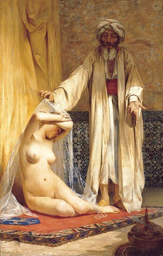 Man in turban and robes unveiling nude seated slave woman