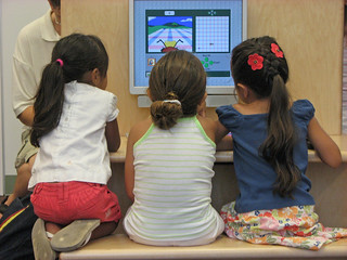 Three girls using the computer at the grand opening.