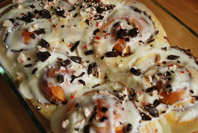 Peppermint Bark Buns - sweet rolls stuffed with chocolate, topped with white chocolate cream cheese frosting, and sprinkled with peppermint bark. Perfect Christmas breakfast!