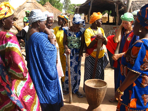 African women gathered around a mortar that looks strikingly like a djembe, ready to pound millet