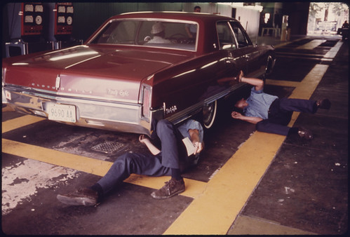 Public Works Department Employees Inspect the Exhaust System for Visible Leaks at an Auto Emission Inspection Station in Norwood, Ohio...08/1975