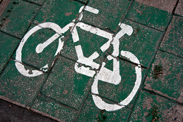 White bike sign on green tiled sidewalk