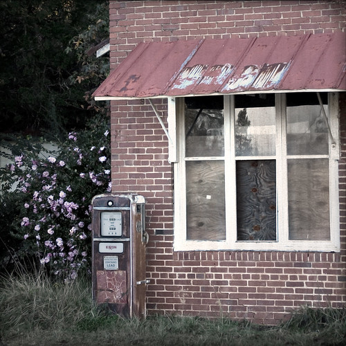 abandoned boardedup gaspump oldcountrystore thecameliaisstillblooming