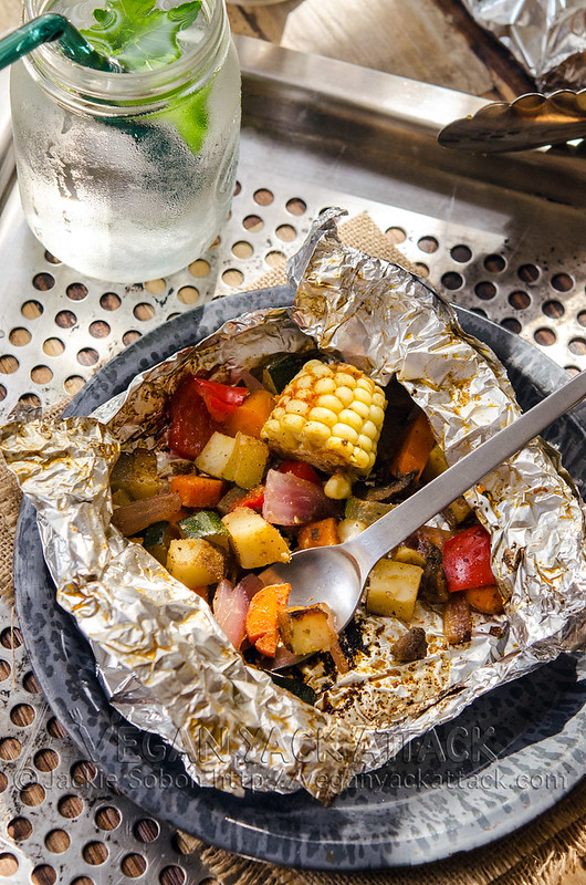 Foil, grilled, BBQ Party Pack opened up with veggies showing, being eaten with a spork