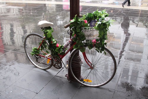 Fake flowers tied around a parked bike advertising a clothes shop on Bourke Street