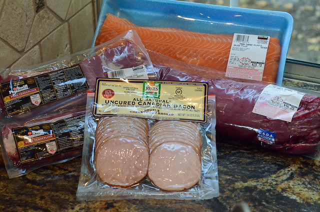 Canadian bacon in a package next to packages of pork tenderloin and a large salmon filet.