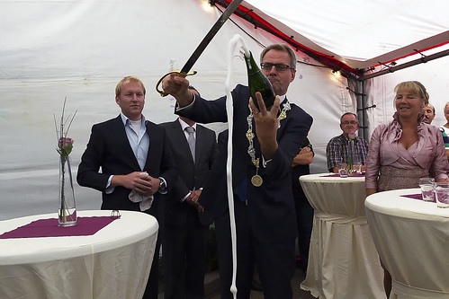 Burgemeester Polman opent een fles champagne en daarmee Uitvaart Verzorging West-Brabant