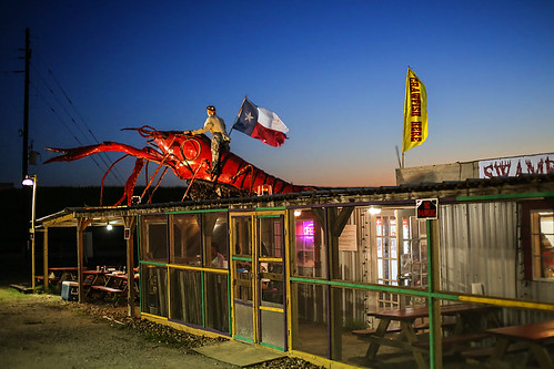 texas waller wallercounty crawfishshack gaintcrawfish restaurant flags cowboy fiigure street road tree cones parkinglot sunset twilight lights signs
