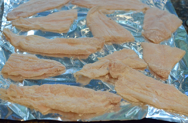 Pieces of flour coated fish on foil.