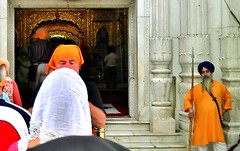 Guard watching tourists preparing to enter the temple. Gurudwara Bangla Sahib, sikh temple in Delhi