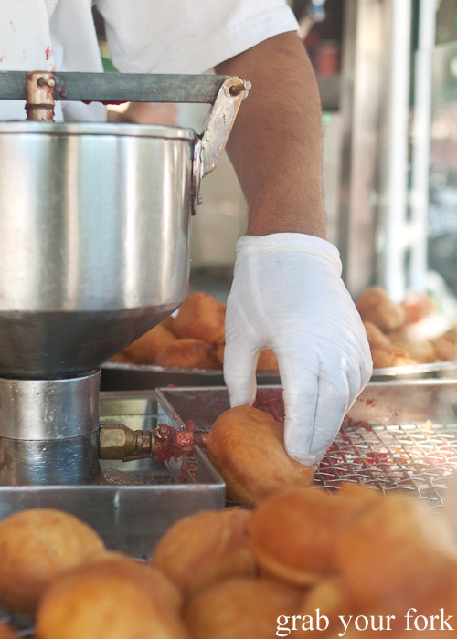 Injecting raspberry jam into fresh cooked doughnuts at American Doughnut Kitchen, Queen Victoria Market, Melbourne