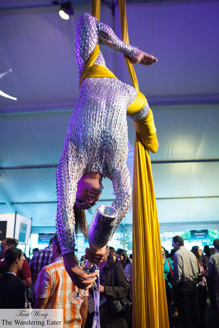 An aerial contortionist pouring Prosecco for guests